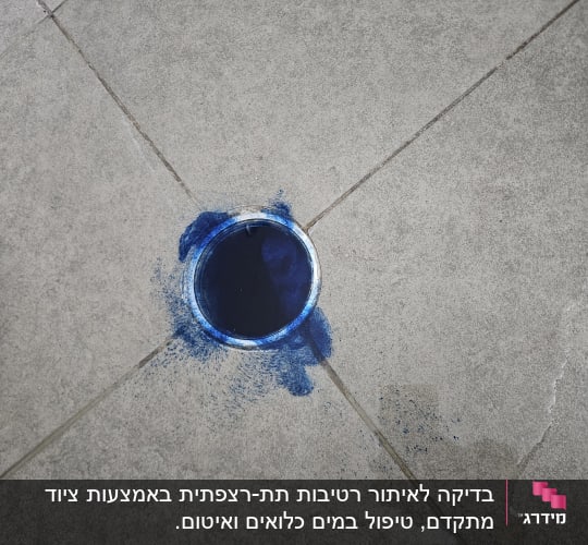 ניקוז עם סימני צבע כחול על רצפה אפורה